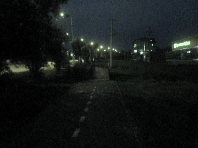a dark asphalt path lined by distant streetlights