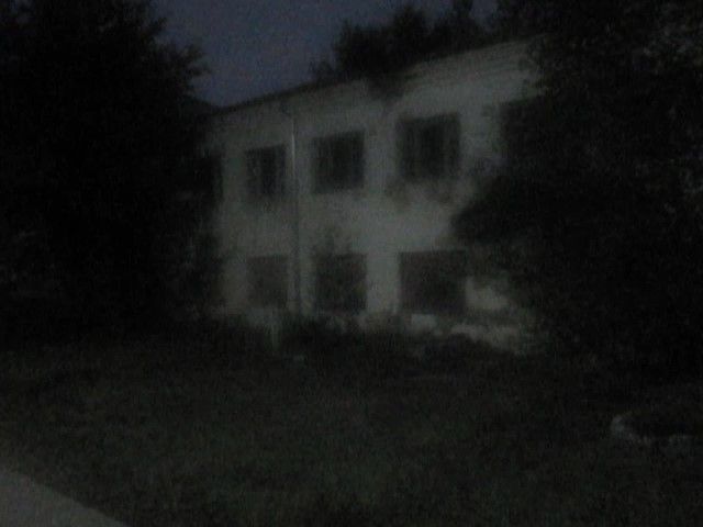two-story weathered building surrounded by dark trees in the night