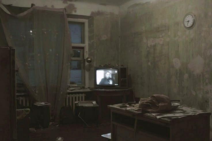 a room in dim light with a small CRT television broadcasting on a table
