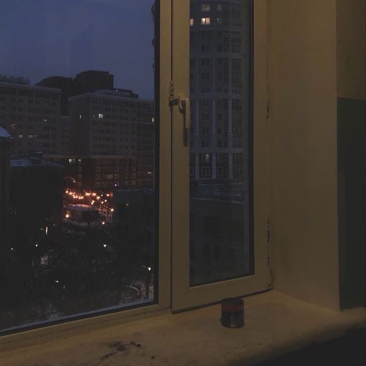 view through a window at night towards city lights, candle on the sill