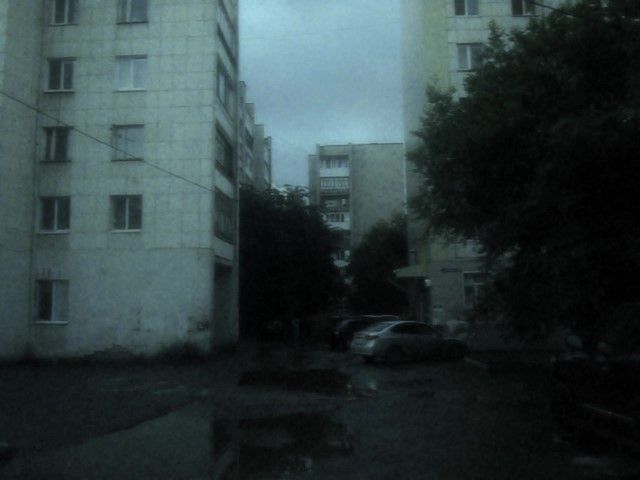 overcast Soviet-style concrete apartment blocks with reflections in parking lot puddles
