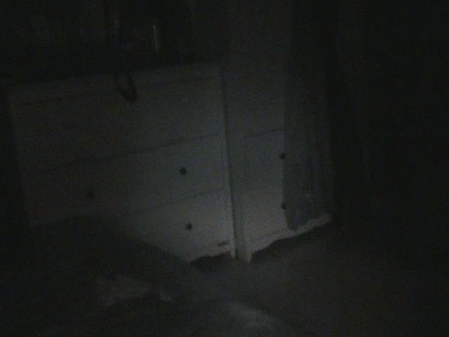 white dresser in near-total darkness, faint ambient light on drawer handles